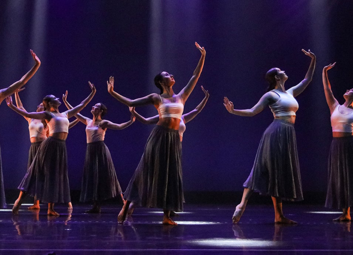 Dancers on stage hold their hands in the air.